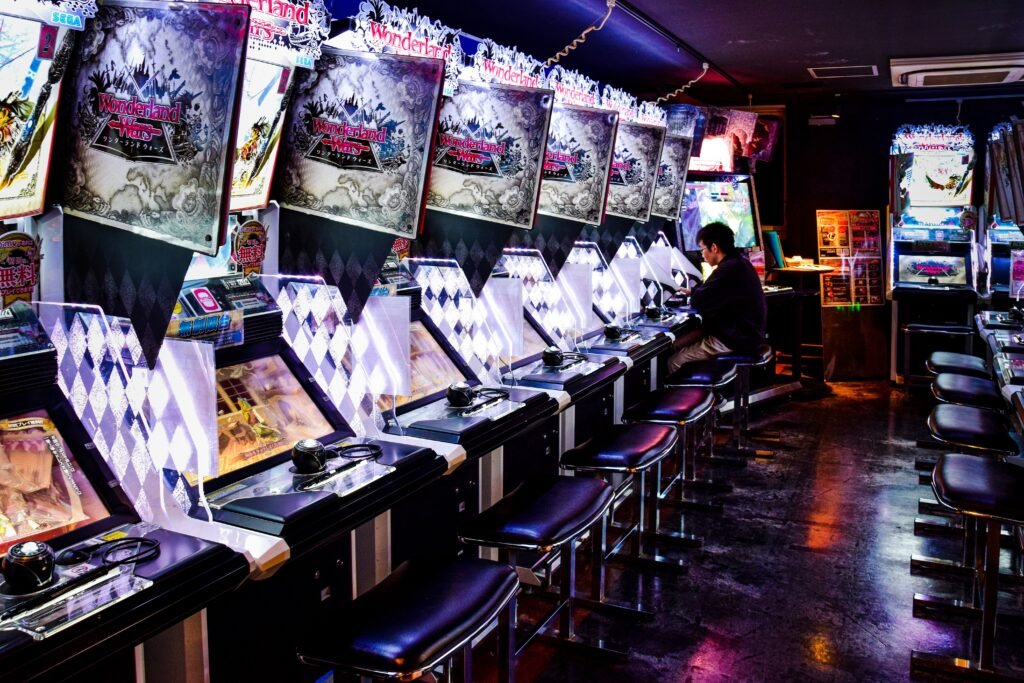 A man plays inside a modern arcade in Tokyo, illuminated by neon lights and gaming machines.