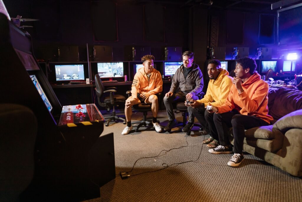 A group of young men having fun gaming together indoors, using controllers and arcade machines.