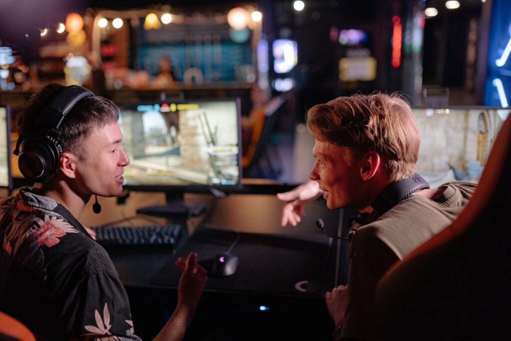 Two young men enjoying a lively video game session in a dimly lit gaming arena.